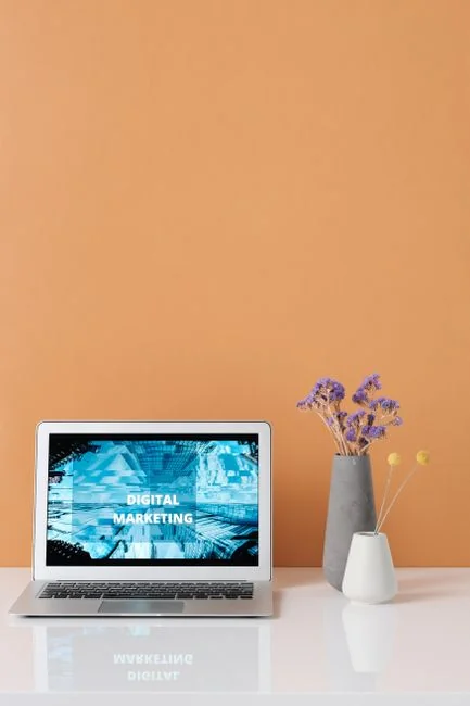 A clean flat-lay composition featuring a credit card, a laptop, and a small shopping cart.